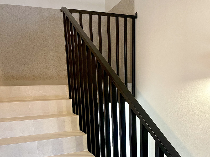 Wewnętrzna klatka schodowa z czarną stalową balustradą o prostym nowoczesnym designie.